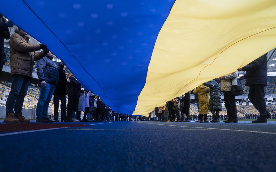 Ukrainian government workers carried a large Ukrainian flag around Olimpiysky Stadium during a government declared “Unity Day” in Kyiv, Ukraine, on Feb. 16, 2022. 