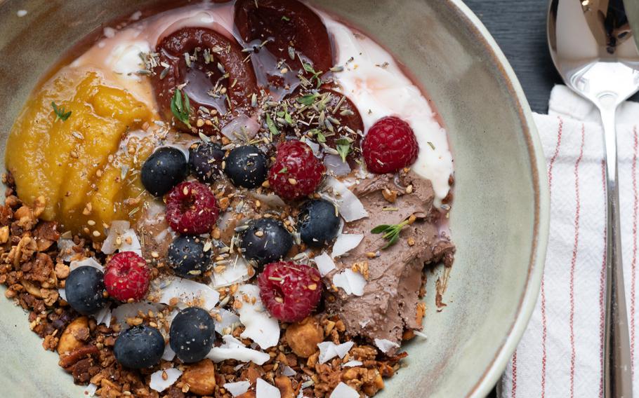 A bowl filled with granola and fruit sits on a table.