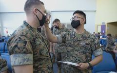 A Navy corpsman takes a Marine's temperature before he departs MCAS Iwakuni, Japan, for Guam on June 17, 2021. 
