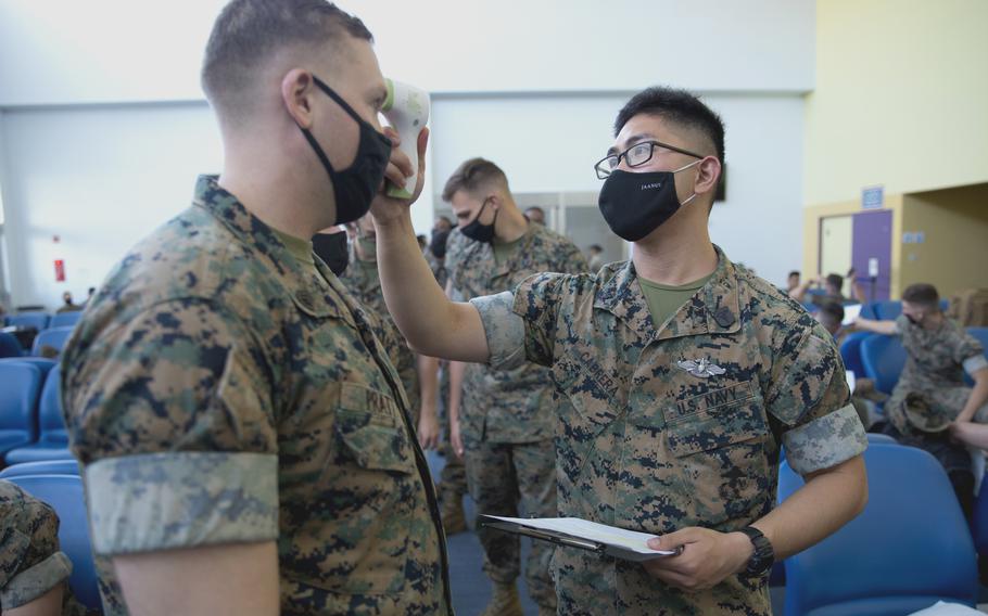 A Navy corpsman takes a Marine's temperature before he departs MCAS Iwakuni, Japan, for Guam on June 17, 2021. 