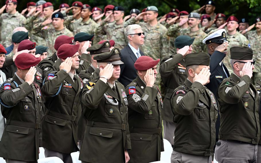 Uniformed troops salute in formation.