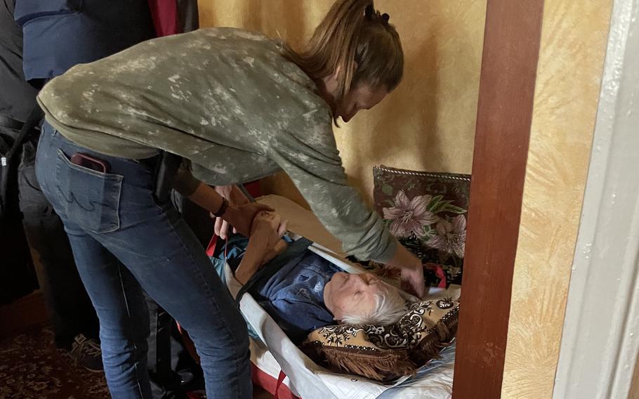 A volunteer helps prepare Nelya Kamynina, 92, for evacuation from her home in Bakhmut. 