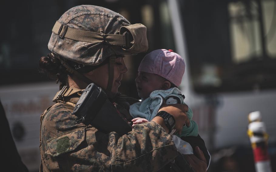 A U.S. Marine calms an infant at the international airport in Kabul, Afghanistan, on Aug. 28, 2021. The upcoming one-year anniversary of the U.S. withdrawal from Afghanistan could induce moral injury resulting from trauma about the outcome of the 20-year-long war.