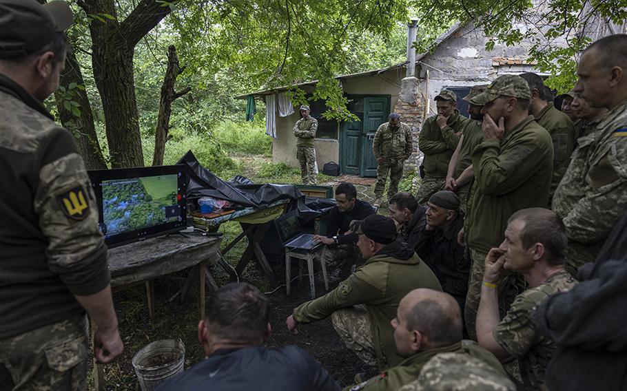Ukrainian soldiers watch footage of their tank maneuvers.