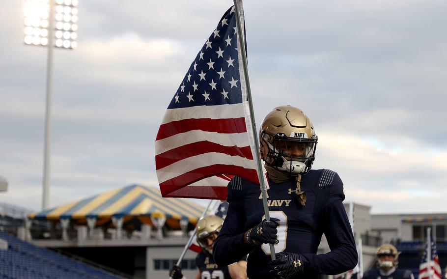 Navy's Cameron Kinley carries a U.S. flag as the team takes the field against Tulsa at Navy-Marine Corps Memorial Stadium on December 5, 2020, in Annapolis, Md.