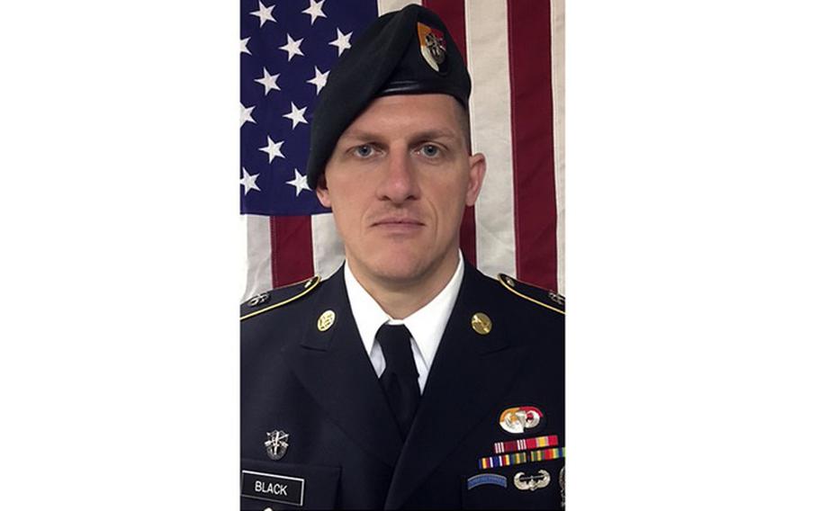 Portrait of an Army officer in dress uniform and beret standing in front of a U.S. flag.