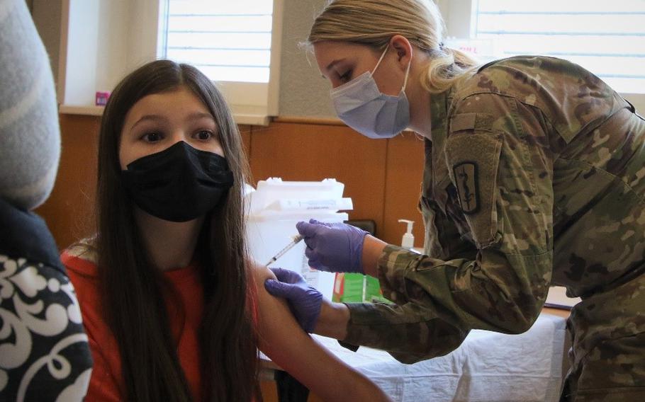 Army Spc. Kensey Frazee, a licensed practical nurse with the 167th Medical Augmentation Detachment, 30th Medical Brigade, provides a COVID-19 booster shot to Heidi Hall, 13, at Landstuhl Regional Medical Center in Germany, Jan. 6, 2022. German schools are ending mask requirements for students later this month. Defense Department schools are reviewing their policies but haven't announced any decisions.