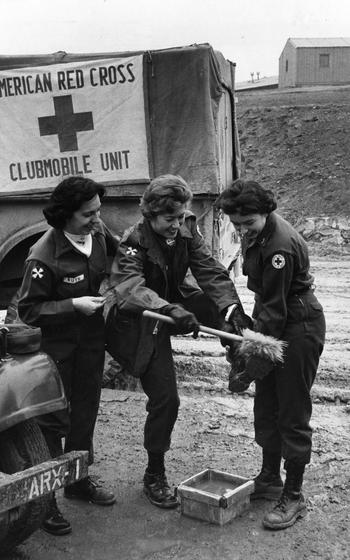 Two women help another woman off a vehicle