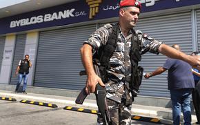 Lebanese security officers stand outside a Byblos Bank branch that was broken into by depositor Ali Hodroj holding a handgun, firing a warning shot and demanding about $40,000 of his trapped savings, in Tyre, south Lebanon, Tuesday, Oct. 4, 2022. Hodroj retrieved about $9,000 in Lebanese pounds following negotiations before he turned himself in to police outside the branch. Lebanese depositors, including a retired police officer, stormed at least four banks in the cash-strapped country Tuesday after banks ended a weeklong closure and partially reopened. (AP Photo/Mohammed Zaatari)