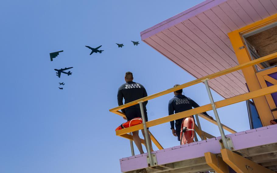 Lifeguards watch an aircraft formation in the air