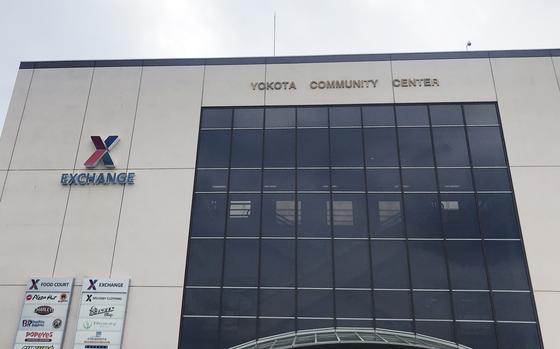 A military exchange building is seen from below, with large windows and signage reading “Yokota Community Center.”