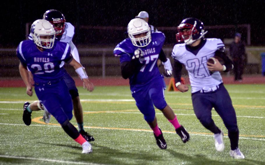 Lakenheath’s Lucius Bowman runs away from Ramstein’s Matthew Rutlege, center, and Ethan Wilson during Friday evening’s game in Ramstein, Germany