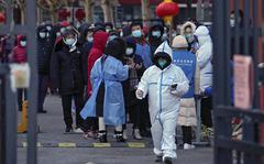 Residents wearing face masks to help protect from the coronavirus gather in line as they wait for a throat swab at a COVID-19 test site outside a residential housing block in Fengtai District in Beijing, Wednesday, Jan. 26, 2022. The Chinese capital reported an uptick more than dozen daily new COVID-19 cases as it began a third round of mass testing of millions of people Wednesday in the run-up to the Winter Olympics. (AP Photo/Andy Wong)