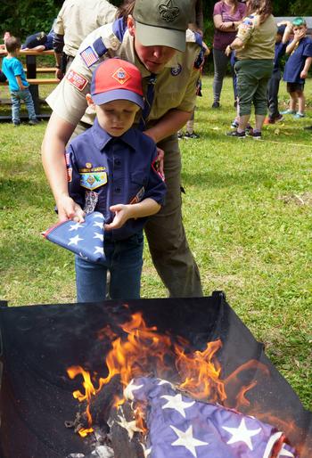 Yokosuka Pack 33 Cubmaster Susan Duenas helps a Cub Scout retire an American flag at Ikego West Valley Campground near Yokosuka Naval Base, Japan, May 6, 2023.