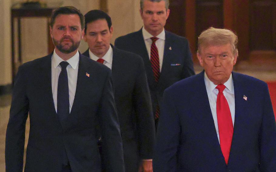 Trump, Vance, Rubio and Hegseth walk along a red-carpeted hallway in the White House.