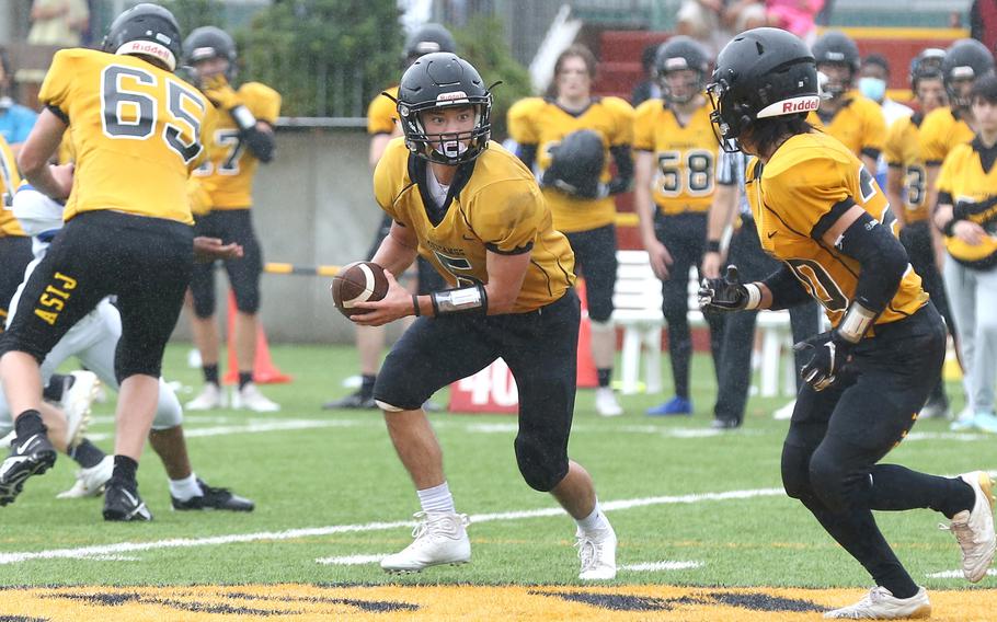 American School In Japan quarterback Joey Schulz prepares to hand off to Noa Grasse during Saturday's rain-drenched Kanto Plain football game at Mustang Valley. The Mustangs led 14-6 with 9:42 left when the game was called due to lightning and rescheduled for Oct. 28 at Yokota.