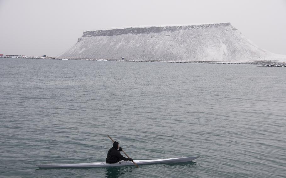 With Mount Dundas in the distance, Outdlaq Qujaukitsoq moves his kayak into position to demonstrate how the native Inuit use the boats to hunt and fish. Qujaukitsoq and another man spent about 20 minutes rolling their kayaks in the icy water.