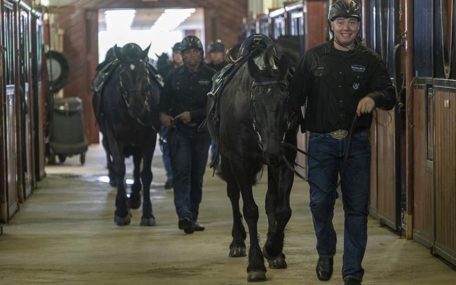 Soldiers lead their horses into the stable.