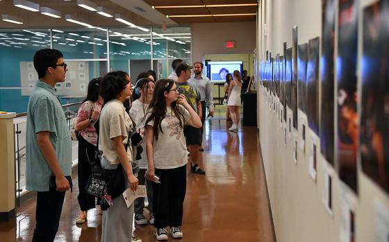 Students and visitors look at photographs on display.