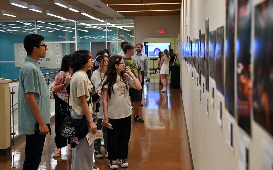 Students and visitors look at photographs on display.