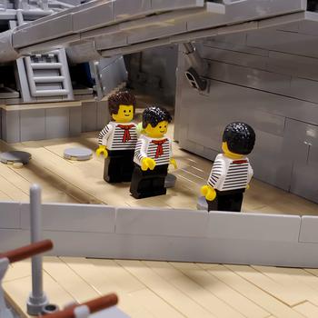 A close-up view of three small LEGO figures dressed as sailors on a LEGO ship