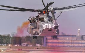 Colored oil smoke surrounds a CH-53K King Stallion at Naval Air Station Patuxent River, Md., in 2019. The bulk of the Navy’s CO2 emissions come from ships and aircraft, but those platforms are the hardest to decarbonize because of the amount of energy they require and the missions they perform.