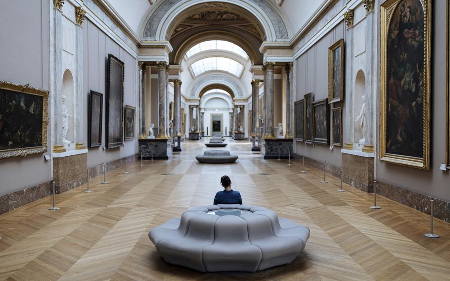 A woman observes paintings inside the Louvre Museum in Paris, Tuesday, July 26, 2022. The museum benefits from one of Paris' best-kept secrets, an underground cooling system that's helped the Louvre cope with the sweltering heat that has broken temperature records across Europe.
