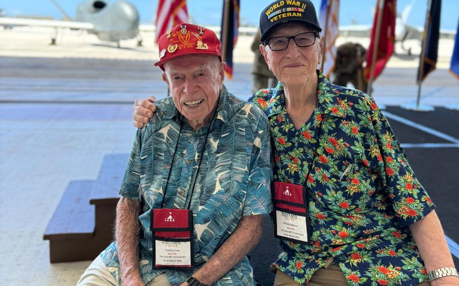 Two WWI veterans pose for a picture while wearing baseball caps and hawaiian shirts.