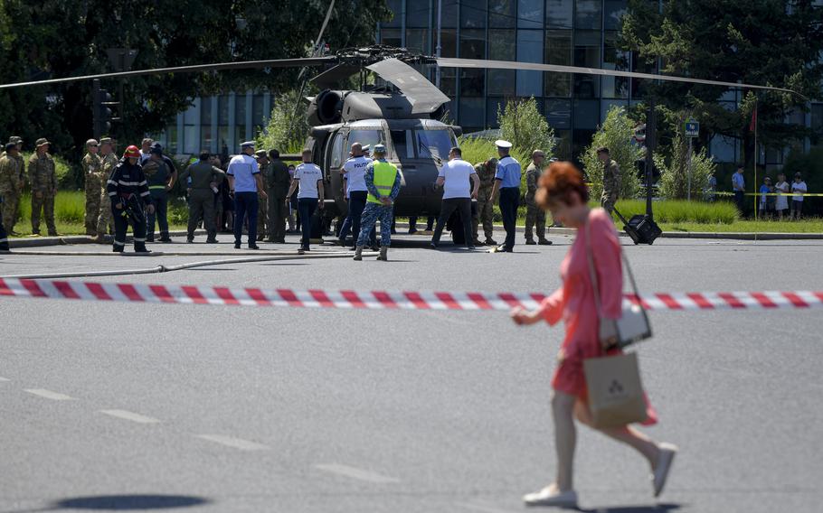 Soldații trec pe lângă un elicopter Black Hawk militar american după o aterizare de urgență pe o stradă aglomerată din București, România, joi, 15 iulie 2021. Un elicopter Black Hawk militar american a participat la pregătirile pentru Ziua Zborului Românesc, care este programat să înceapă pe 20 iulie, au fost obligați să aterizeze pe o stradă aglomerată din București joi dimineață, avariază două mașini după ce au căzut două lampioane.  Nu s-au raportat răni. 