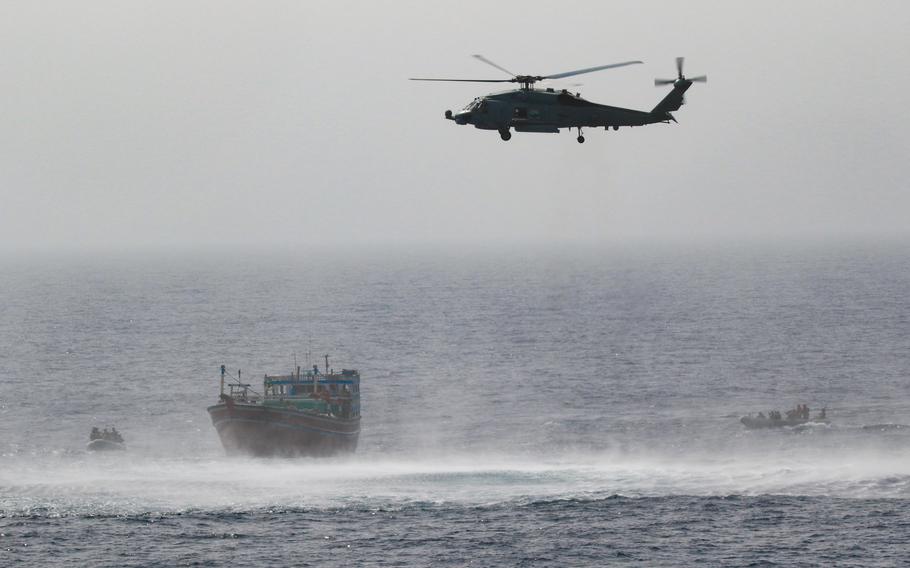 An MH-60R Seahawk from Helicopter Maritime Strike Squadron 35, Detachment 1, provides aerial support to an interdiction team from the destroyer USS Momsen, as it approaches fishing vessel, May 16, 2022. The vessel was seized in international waters in the Gulf of Oman. 