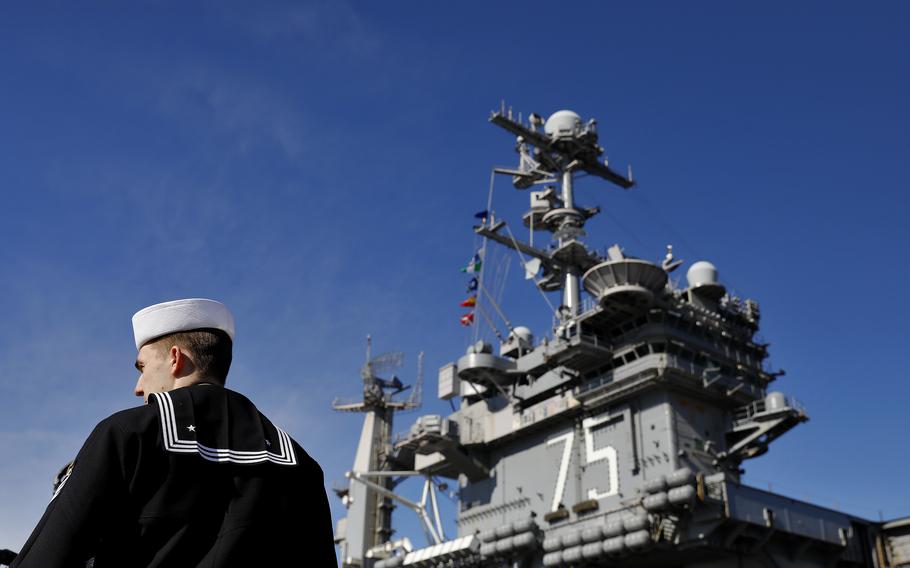 A sailor stands on a pier next to the USS Harry S. Truman before to deploying from Naval Station Norfolk on Dec. 1, 2021.