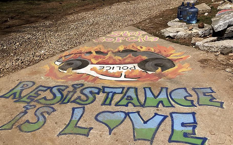 A mural depicting a burning police cruiser sits at the entrance to the forest where a police training center is scheduled to be built. 