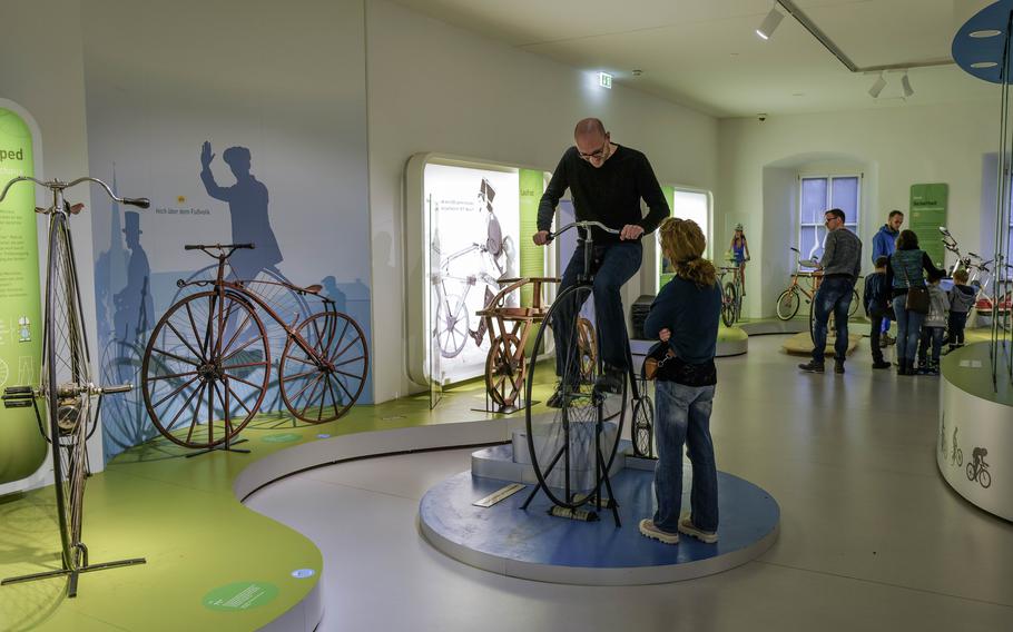 A visitor climbs a penny-farthing bicycle at the German Motorcycle Museum in Neckarsulm, Germany, Jan. 21, 2024. The penny-farthing style bicycles lacked gear sprockets and chains and made use of a very large front wheel, which turned at the same speed as the pedals, and a small rear wheel for support.