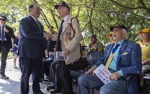 A man in a suit shakes hands with an elderly veteran.