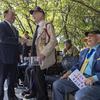 A man in a suit shakes hands with an elderly veteran.