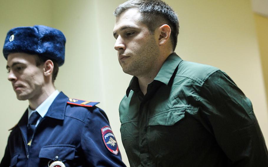 Police officers escort U.S. ex-Marine Trevor Reed, charged with attacking police, into a courtroom prior to a hearing in Moscow, Russia on March 11, 2020.