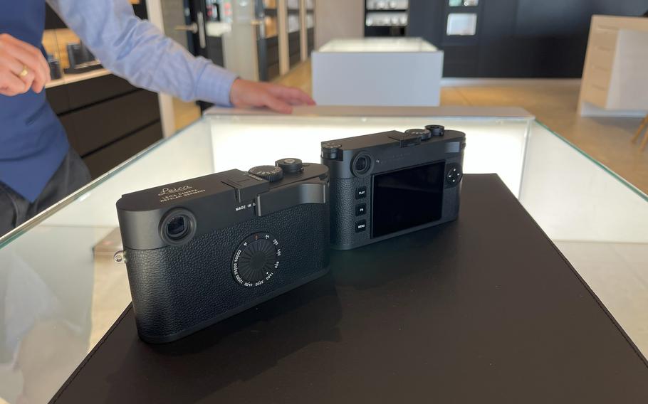 Two black Leica cameras sit side by side on a display counter.