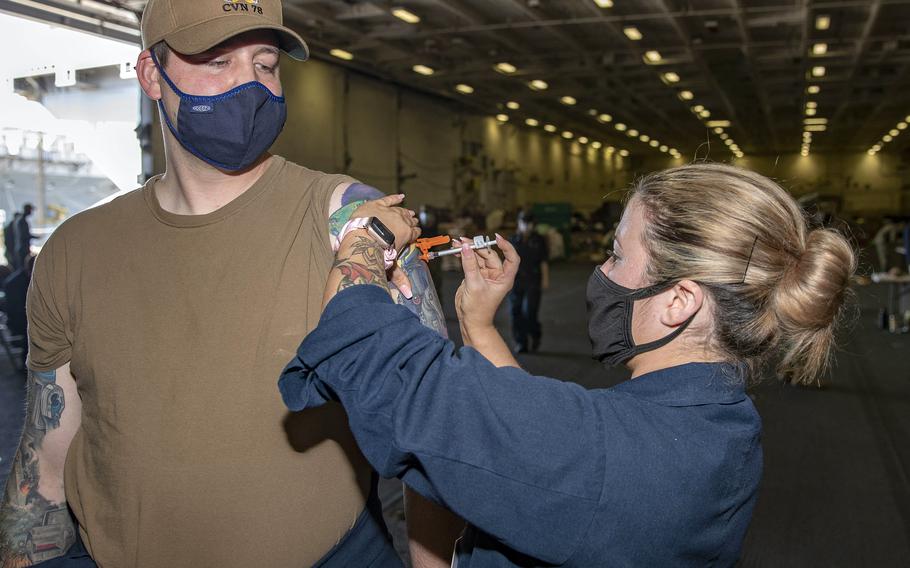 Petty Officer 3rd Class Ricquel Boucher administers a COVID-19 vaccine to Chief Warrant Officer 2 Christopher Dearing in the USS Gerald R. Fords hangar bay, May 5, 2021. Sailors fully vaccinated against COVID-19 can now make some port calls, remove their masks and deploy without quarantining beforehand, the Navy has announced. 