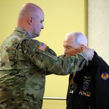 Brig. Gen. David Doran, assistant director, Army National Guard for Aviation, Intelligence and Information presents Capt. Dick Nelms, World War II pilot with the Knight of the Honorable Order of Saint Michael award at the Washington Army National Guard Aviation Readiness Center, Joint Base Lewis-McChord, Wash., on Sunday, March, 3, 2024.