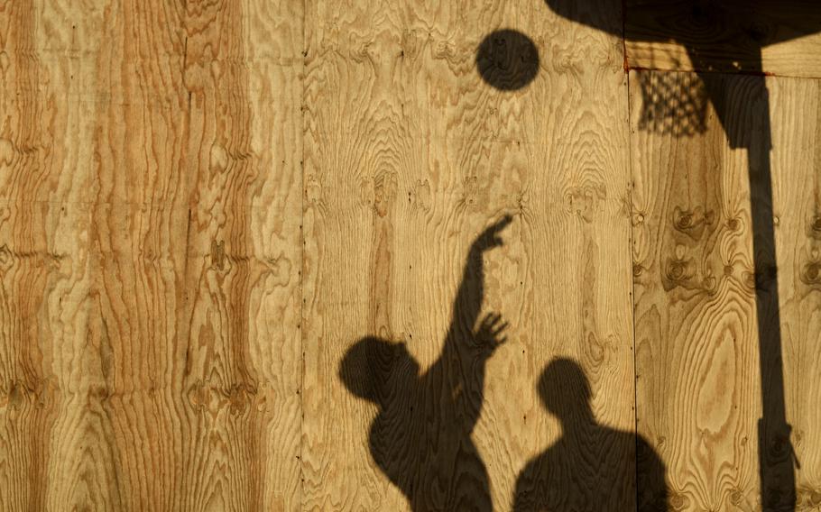The evening sun casts the shadows of Spc. Christopher Tenore, left, and Sgt. Nicholas Streeter as they play basketball at Combat Outpost Sabari, Khost province.