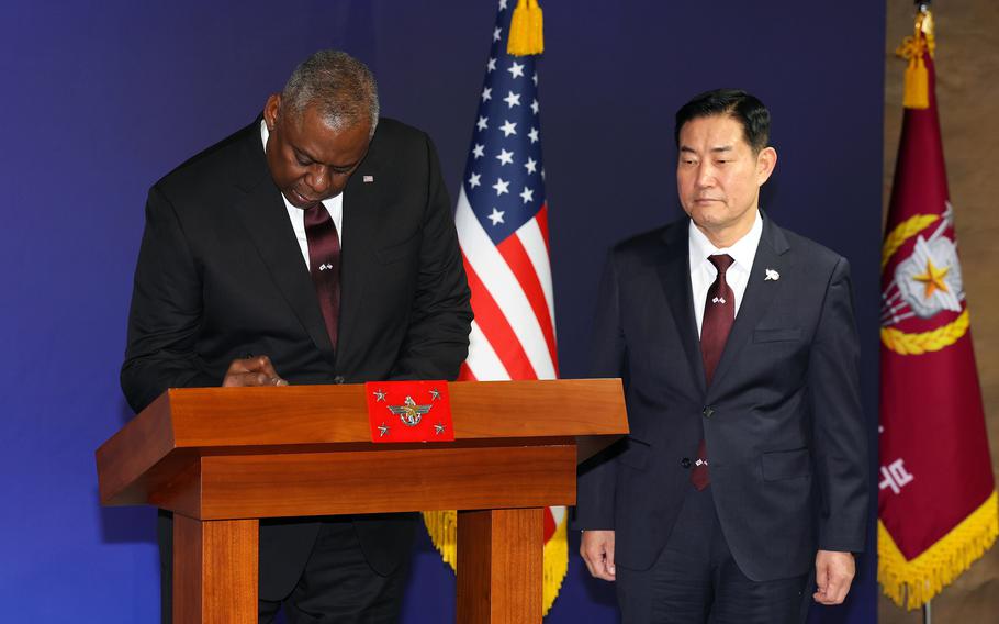 Secretary of Defense Lloyd Austin signs a guestbook at the Ministry of National Defense headquarters ahead of his meeting with Defense Minister Shin Won-sik, right, in Seoul, South Korea, Monday, Nov. 13, 2023. 