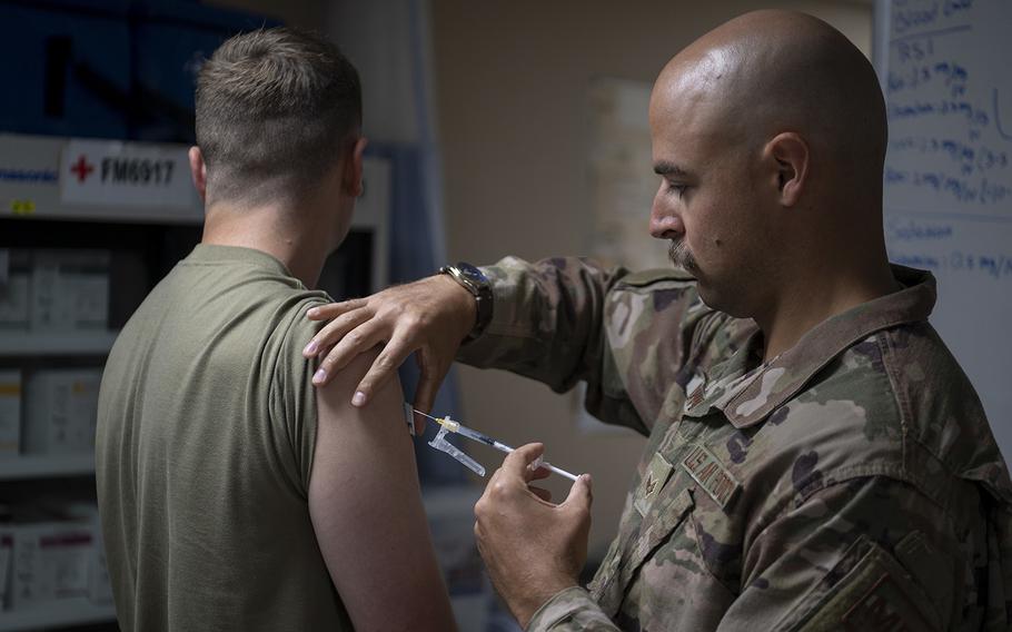 Senior Airmen Caleb Beaver, an emergency medical technician with the 332d Expeditionary Medical Squadron, administers a COVID-19 booster to an Airman at an undisclosed location in Southwest Asia on Oct. 20, 2022. 