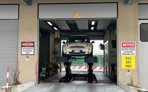 A white car sits on a lift at an inspection bay in Torri di Quartesolo, Italy.