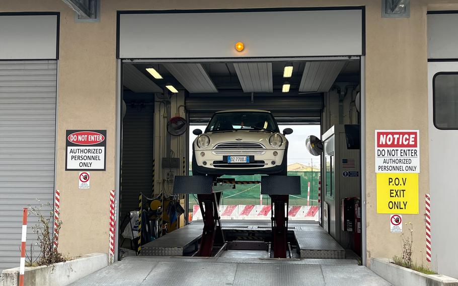 A white car sits on a lift at an inspection bay in Torri di Quartesolo, Italy.