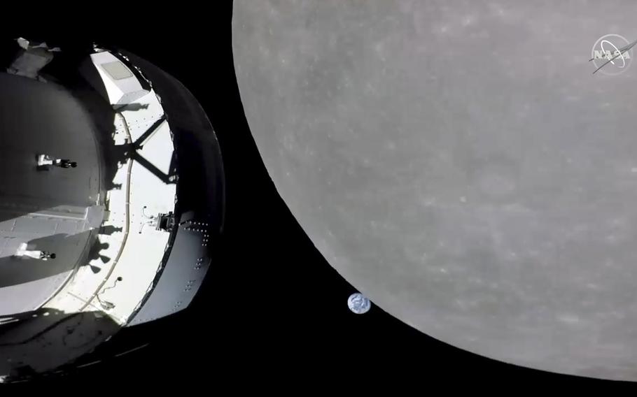 This screengrab from NASA TV shows NASA’s Orion capsule, left, nearing the moon, right, Monday, Nov. 21, 2022. At center is earth.