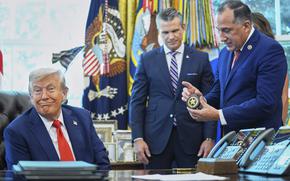 Director of U.S. Federal Marshall Service, Gadyaces Serralta, right, presents President Donald Trump with an honorary badge, as Secretary of Defense Pete Hegseth looks on, in the Oval Office of the White House, Monday, Aug. 25, 2025, in Washington. (AP Photo/Evan Vucci)