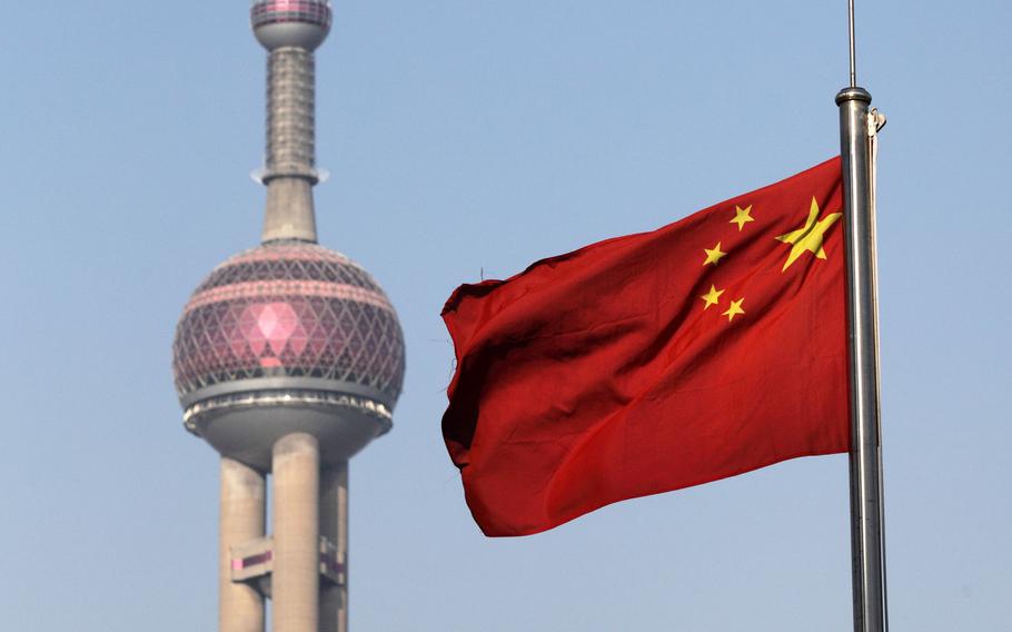 China’s national flag flies as the Oriental Pearl Tower stands in Shanghai on Jan. 28, 2013.