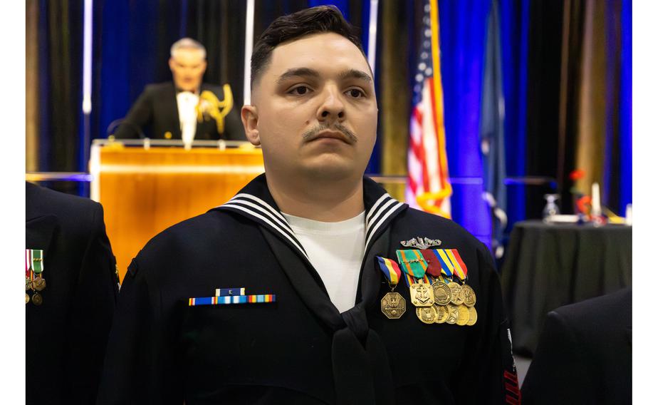 A decorated sailor stands at attention during a ceremony