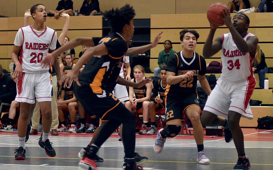 Kaiserslautern's Xavier Nelson goes up to shoot while Spangadahlem's Robert Legett, left, and Casey Supinger  defend during a game Friday at Kaiserslautern High School in Kaiserslautern, Germany. Far left is the Raiders' Jason Quarles.