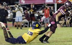 Guam High's Cameron Brantley tries to get a hand on Father Duenas Memorial quarterback Alex Sojo.